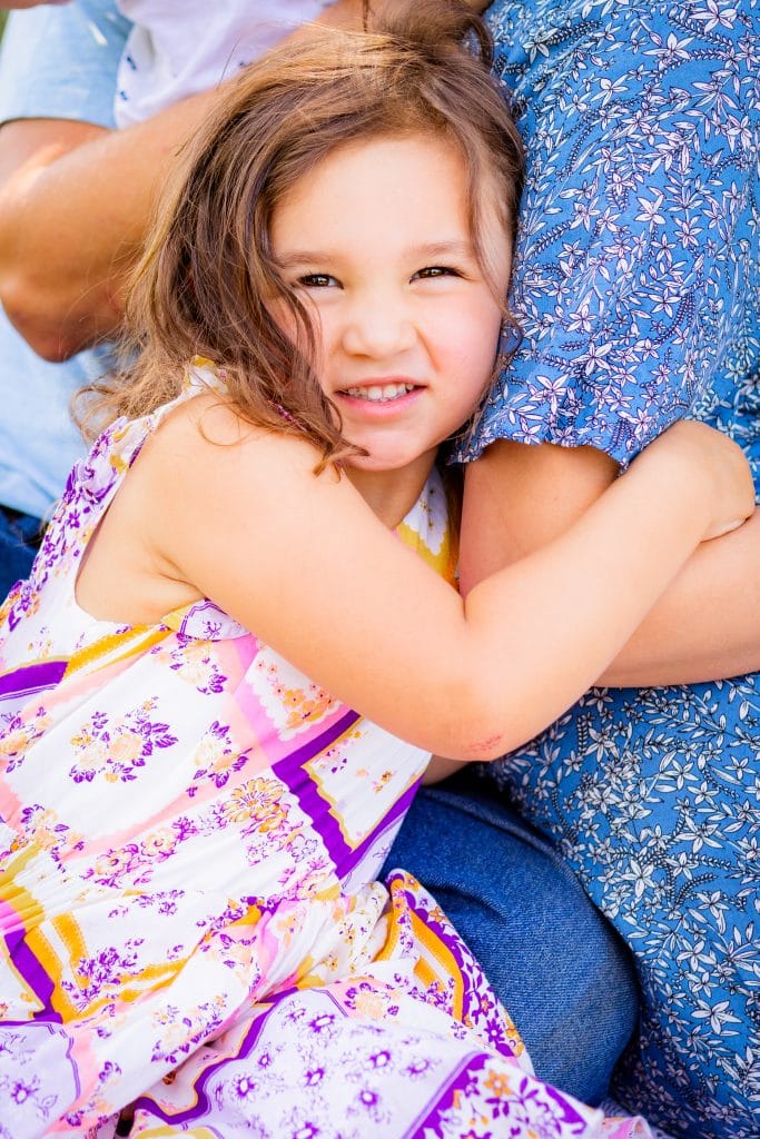 Daughter snuggles mom and smiles big during summer family picture session