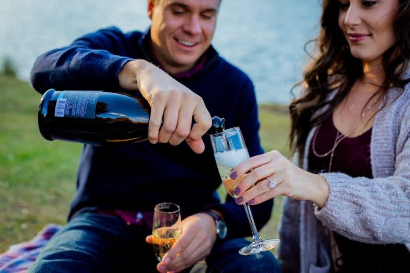 man and woman sharing champagne at engagement portrait session