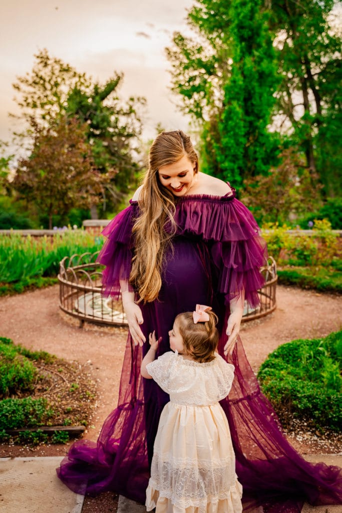 Maternity Photographer, a pregnant and expecting mother dances with her young daughter outdoors