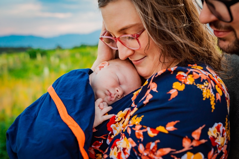 Newborn Photographer, a mother holds her baby child on her chest outside