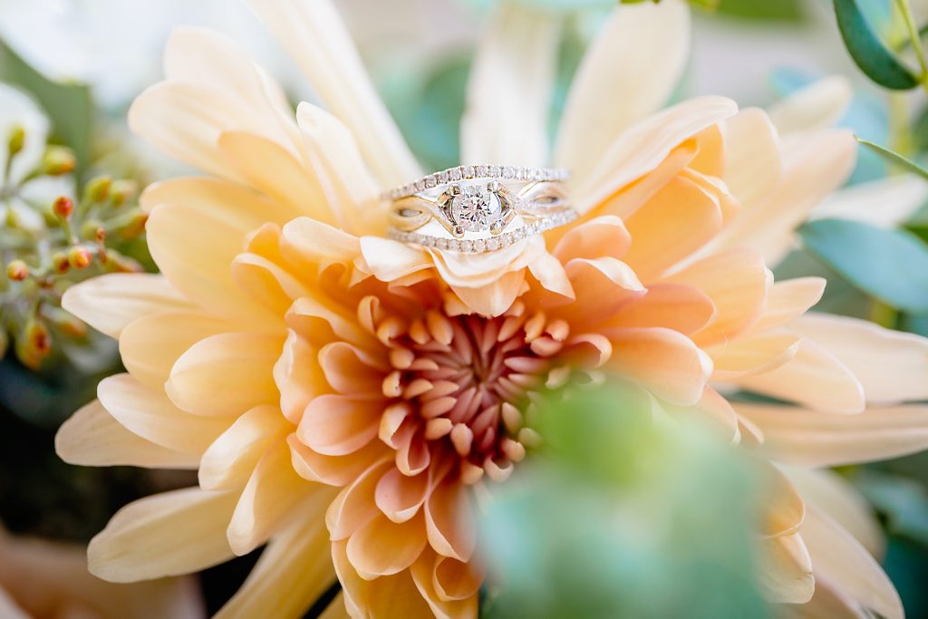 Wedding Photographer, a wedding and. engagement ring sit atop flower