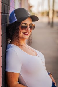 woman standing with aviator glasses leaned against building