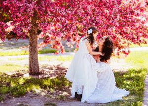 mother and daughter embracing in front of blooming tree
